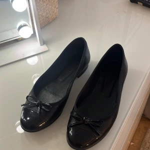 Svarta ballerinaskor med rosett - Säljer ett par klassiska svarta ballerinaskor med liten rosett framtill. Jag säljer dom endast för 100!!