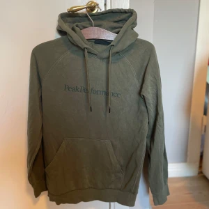  Peak Performance hoodie - Säljer en olivgrön hoodie från Peak Performance med broderad logga på bröstet. I storlek S, väldigt fint skick 8.5/10, inga tydliga bevis på användning.
