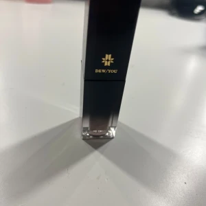 Dew/You flytande läppglans i nude - Snyggt läppglans från Dew/You i en stilren fyrkantig förpackning med svart lock och transparent botten. Färgen är nude med en lätt glansig finish. Säljer den för att jag inte tycker om den. Använd 2 gånger 