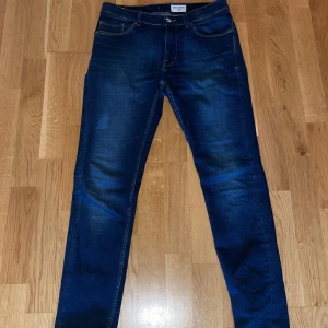 blå jeans tiger of Sweden  - Säljer ett par mörkblå jeansbyxor från Evolve med klassisk femficksdesign och raka ben. Jeansen har snygga slitningar och kontrastsömmar, perfekta till vardagslooken. Modellen är normal passform och tillverkad i jeansmaterial.