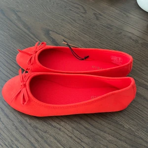 Röda ballerinaskor med rosett - Säljer ett par snygga röd/oranga ballerinaskor med rund tå och söt rosettdetalj framtill. Helt nya säljer pga för stora. Jag har vanligtvis 37, dessa är i 36 och är för stora. Skulle alltså passa någon med runt 38❤️