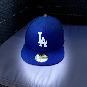 Blå LA keps från New Era 59FIFTY - Snygg blå keps från New Era 59FIFTY med LA-logga framtill och MLB-logga bak. Klassisk rak skärm och broderade detaljer. Perfekt för dig som gillar sportig stil.