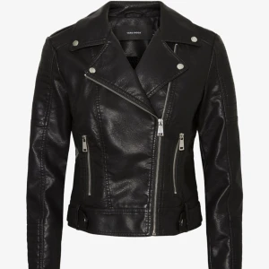 Svart skinnjacka från Vero Moda - Snygg svart skinnjacka med klassisk bikerstil från Vero Moda. Jackan har silvriga dragkedjor, knappar och detaljer, samt breda slag. Passformen är normal och jackan har långa ärmar med dragkedjor vid ärmsluten. Ej riktigt läder. Oanvänd.