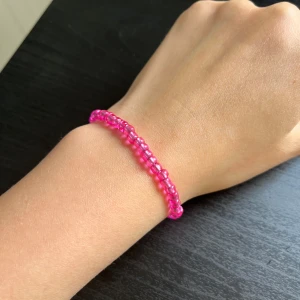 Hot pink pärlarmband - Säljer ett handgjort armband med små rosa pärlor. Armbandet har en enkel och söt design som passar perfekt till att liva upp din outfit. Elastiskt band gör det lätt att ta på och av.