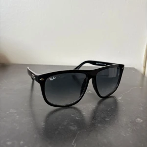 Ray-Ban boyfriend  - Klassiska svarta solglasögon från Ray-Ban med fyrkantig form och mörka glas. Snygg och tidlös design med Ray-Ban-logga på linsen och metallnitar vid bågarna. Perfekta för soliga dagar.