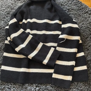 Svart och vitrandig stickad tröja från Samsa Collection - Säljer en svart stickad tröja med vita horisontella ränder från Samsa Collection. Tröjan har lång ärm och en klassisk, avslappnad passform. Perfekt för dig som gillar stilrena basplagg med lite extra detalj.