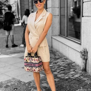 Beige ärmlös kavajklänning - Snygg beige ärmlös kavajklänning med dubbelknäppning och krage. Klänningen har fickor framtill och en stilren, elegant look. Perfekt för dig som gillar en chic och modern stil.