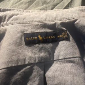 Ljusblå skjorta från Ralph Lauren - Säljer en klassisk ljusblå skjorta från Ralph Lauren med broderad logga på bröstet. Skjortan har lång ärm, krage och knäppning framtill. 