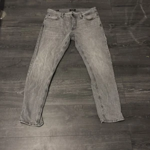 Grå tapered jeans Tapered/Mike 32/32 - Säljer ett par grå jeans i modellen Tapered/Mike med snygg tvättad look. Jeansen har klassisk femficksdesign och avsmalnande ben. Perfekta för dig som gillar en modern och avslappnad stil. Materialet är jeans och färgen är ljusgrå. Använd fåtal gånger