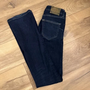 Zara mörkblå bootcut jeans - Mörkblå Zara jeans med klassisk bootcut passform. Jeansen har kontrastsömmar. Jeansen är knappt använd men dem är långa o benen därav har dem fått en slitning längs ner. 