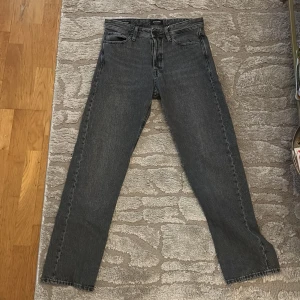 Grå jeans Jack & Jones Relaxed/Chris - Säljer ett par grå jeans från Jack & Jones i modellen Relaxed/Chris. Jeansen har en avslappnad passform med raka ben och klassisk femficksdesign. Tillverkade i slitstarkt denimtyg och passar perfekt till en chill vardagsstil.