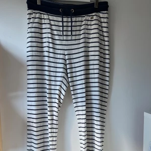 Randiga pyjamas från Hampton Republic - Säljer mjuka randiga pyjamasbyxor från Hampton Republic i vitt med marinblå ränder. Byxorna har en midja med dragsko och resår, samt sidfickor. Byxbenen har även mudd längst ner. Dessa är använda, men fortfarande i bra skick! De har inga fläckar eller märken!