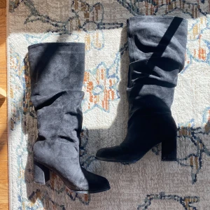 Boots  - Säljer ett par svarta stövlar med hög klack och spetsig tå. Stövlarna har en slouchy passform och går upp till knäna. Perfekta för att lyfta vilken outfit som helst och ger en cool vibe. Storlek 40