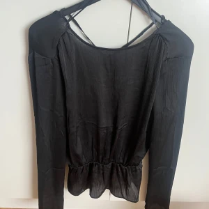 Fin svart blus med knytning i ryggen  - En supersöt blus med resår i midjan och knytning i ryggen, passar till många olika tillfällen 🥰använd en gång! 