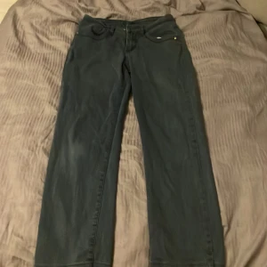 Mörkgröna raka byxor Green House - Snygga mörkgröna byxor från Green House i rak modell. Byxorna har klassiska fyra fickor, bälteshällor och stängs med knapp och dragkedja. Perfekta för dig som gillar en enkel och stilren look.