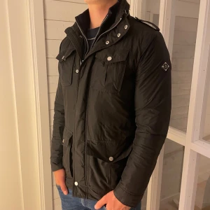 J.Lindeberg Field Jacket - Säljer riktigt snygg field jacket från J.Lindeberg som är fodrad vilket gör den perfekt nu under hösten men även i vinter.  Den har flera fickor på framsidan och även tre innerfickor. Jackan är i storlek S men sitter lite stort i storleken så passar om du har M också. Jackan är väldigt bra skick utan några defekter. Priset kan diskuteras vid snabb affär, hör av dig vid minsta fråga. 