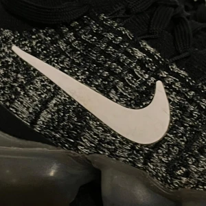 Nike Air Vapormax Flyknit svart/vit - Nike Air Vapormax Flyknit sneakers i svart och vitt med stickad ovandel och tydlig vit swoosh. Skorna har genomskinlig, bubblig sula och svarta skosnören. Perfekta för dig som gillar sportig och modern stil. Nypris 2600kr är i nyskick!