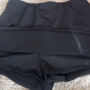 Svart kjol  med shorts - Snygg kjol med shorts, perfekt för sommaren. Kjolen har en enkel och stilren design med hög midja och stretchigt material som sitter bekvämt.