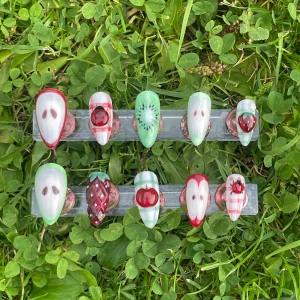 Fruktiga handmålade lösnaglar - Säljer ett set med 10 handmålade lösnaglar med fruktmotiv som äpple, jordgubbe och kiwi. Naglarna har en mix av röd, grön och vit färg med rutiga detaljer och små nyckelpigor. Formen är mandel och oval, materialet är akryl. Perfekt för dig som vill ha unika och färgglada naglar.