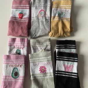 Randiga strumpor med veckodagar🤍 - Säljer ett 6-pack coola strumpor med olika motiv som avokado, fjäril, jordgubbe, blomma och regnbåge.🫶🏻🎀Det är olika veckodagar på strumporna Monday, wendsday,Thursday, Friday, Saturday och Sunday 🤍 De rosa (Friday) har ett litet hål i hälen❤️