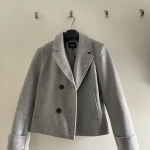 Grå kavajjacka från ONLY, stl M - Snygg grå kavajjacka från ONLY i klassisk modell med bred krage och två knappar framtill. Använd ett par gånger!