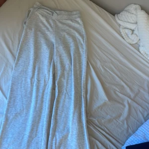 Ljusgrå mjukisbyxor från Gina Tricot - Superbekväma ljusgrå mjukisbyxor från Gina Tricot i storlek S. Byxorna har bred resår i midjan med snörning och raka, lite vidare ben. Perfekta för chill eller när du vill vara extra comfy. Sparsamt använda så skicket är toppen.