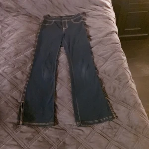 Mörkblå bootcut jeans med kontrastsömmar - Säljer ett par mörkblå jeans med bootcut passform och tydliga kontrastsömmar. Byxorna har klassiska bakfickor och en snygg, markerad midja. Perfekta för dig som gillar en retroinspirerad look med lite utsvängda ben.