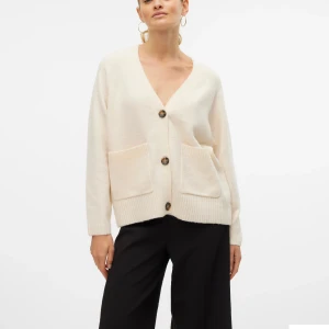 Beige kofta med stora knappar - Mysig beige kofta med v-ringning och stora bruna knappar framtill. Koftan har två stora fickor och ribbade muddar vid ärmslut och nederkant. Perfekt för lager-på-lager och chill dagar. Koftan kommer inte till användning längre