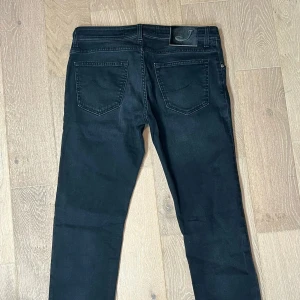 Jacob Cohëns - Snygga svarta jeans från Jacob Cohën. Perfekta för dig som vill sticka ut med en exklusiv look. Storlek: W34 och längd ~105cm. Hör av dig vid minsta fundering.