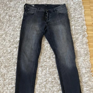 Jack & Jones Slim Glenn svarta jeans - Slim Glenn jeans från Jack & Jones i mörkgrått med svarta toner och diskret tvättad look. Klassisk femficksmodell med smal passform och snygga detaljer på bakfickorna. Perfekta för dig som gillar en stilren och modern vibe.