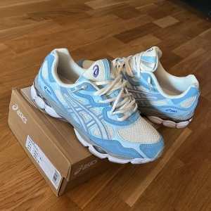 Asics GEL-NYC sneakers blå/vit - Säljer ett par Asics GEL-NYC sneakers i fräscha blå och vita toner. Skorna har mesh och syntetmaterial, med coola detaljer och snörning. Perfekta för dig som gillar sportig stil och vill ha bekväma skor med snygg design. Helt nya oanvända 
