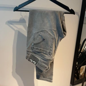 Gråa Dondup jeans med slitningar - Ett par feta Dondup George med slitningar. Perfekt nu till hösten. Skick 8/10. Pris 599kr. Skick är 8/10 på grund av att de finns lagning mar i jeansen men inget som märks vid användning om det är du undrar över då är det bara att fråga.