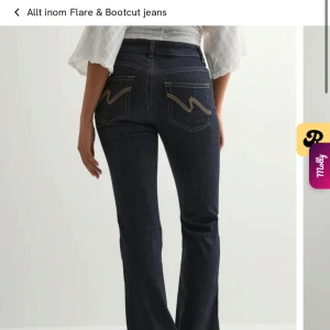 Mid waist bootcut jeans från Nelly - Helt nya, ej använda då dessa är för små. Mörkblå bootcut jeans från Nelly med snygg kontrastsöm och coolt broderi på bakfickorna. Jeansen har midwaist passform och klassisk femficksdesign. Perfekta för dig som gillar en tidlös men trendig look.