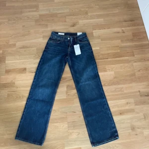 Blå wide jeans från Zara, stl 36 - Snygga blå jeans från Zara i storlek 36 med låg midja och raka, vida ben. Klassisk femficksmodell i jeansmaterial med full längd. Perfekta för dig som gillar en avslappnad och trendig look. Aldrig använda!
