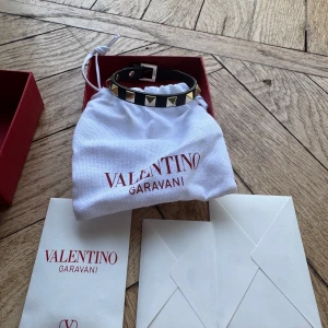 Valentino Garavani armband  - Svart armband  från Valentino Garavani med ikoniska pyramidformade guldfärgade nitar. Perfekt accessoar för att lyfta din outfit med en edgy touch. Knappt använd allt medföljer 