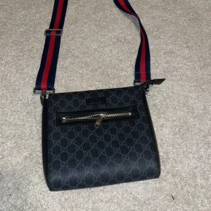 Gucci axelväska - Snygg svart axelväska från Gucci med klassiskt GG-mönster den är lite sönder vid sidan jag har lagt upp bilderna så ni kan se, man ser inte det på långt håll 