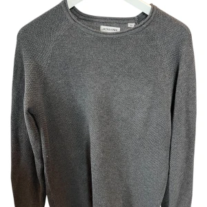 Grå stickad tröja från Jack & Jones storlek S - Snygg grå stickad tröja från Jack & Jones med rund hals och långärmad design. Tröjan har en diskret textur och enkel stil som funkar till jeans eller chinos. Perfekt för dig som gillar en clean look och vill ha något som är både bekvämt och stilrent. Skick 10/10 - Aldrig använt😁🙌 