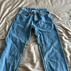 Blå loose fit jeans W31 L32 - Säljer ett par klassiska blå jeans i loose fit med raka ben och fem fickor. Jeansen har en ljusblå tvätt och är tillverkade i bomull. Perfekta för dig som gillar en avslappnad och trendig stil. Nypris 699kr