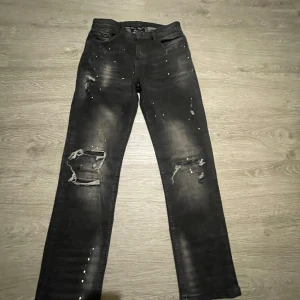 Svarta distressed jeans Supply & Demand PRIS KAN DISKUTERAS  - Svarta jeans från Supply & Demand med slitna detaljer och hål på knäna. Jeansen har en tvättad look med små vita färgstänk och raka ben. Klassisk femficksmodell i stretchig bomullsblandning. Perfekta för en edgy streetstil.
