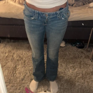 Blå bootcut jeans från Gina Tricot - Säljer ett par blå bootcut jeans från Gina Young i storlek 158. Jeansen har låg midja, snygga broderade detaljer på bakfickorna. De finns inte längre