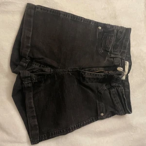 Svarta jeansshorts från Gina tricot  - Snygga svarta jeansshorts från Gina tricot i modellen Molly med klassisk femficksdesign och dragkedja. Perfekta för en avslappnad stil. De har en högmidjad passform som ger en smickrande siluett. Perfekta för sommardagar!