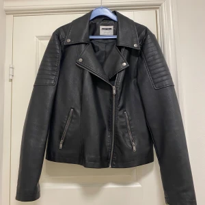 Svart skinnjacka  - Skinnjacka i konstskinn. Väldigt lite använd. Passformen är åt det lösare hållet. 