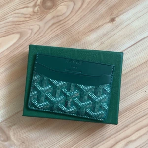 Grön plånbok med mönster - Säljer en elegant grön plånbok. Plånboken har flera kortfack och är perfekt för att hålla dina kort organiserade. Den kommer i en matchande grön förpackning.