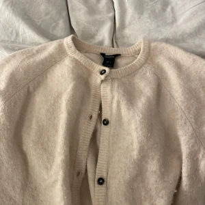 Beige kofta från Lindex - Mysig beige kofta från Lindex i ett fluffigt material. Den har knappar framtill och en rund halsringning. Pyttelite nopprig men annars väldigt fin, storlek Xs . PRIS KAN DISKUTERAS 