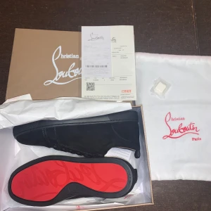 Svarta sneakers från Christian Louboutin - Snygga svarta sneakers i mocka från Christian Louboutin med den ikoniska röda sulan. Skorna har snörning och en stilren design som passar perfekt för den modemedvetna. Levereras med originalförpackning och dustbag. Dessa är ej autentiska 