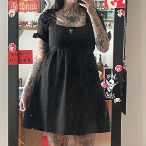 Svart klänning med volangärmar - Säljer en svart klänning med korta puffärmar och en fyrkantig urringning. Klänningen har en lös passform och är perfekt för en stilren look. Den är enkel men elegant och kan stylas på många sätt.