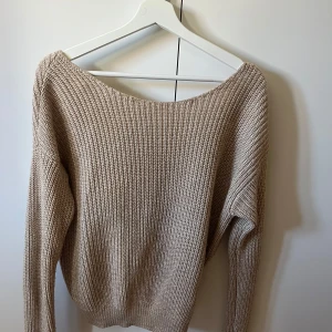 Beige stickad tröja - Säljer en stilren beige stickad tröja med omlott-design i ryggen. I stl. Xs från Nelly 