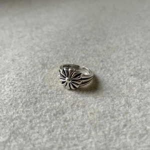 Flower Rockstar Ring - En distinkt silverring i storlek US 7.5 (innerdiameter ca 17,7 mm, omkrets ca 55,5 mm), prydd med ett detaljerat solrosmotiv. En perfekt kombination av rå attityd och tidlös elegans för en unik stilstatement.