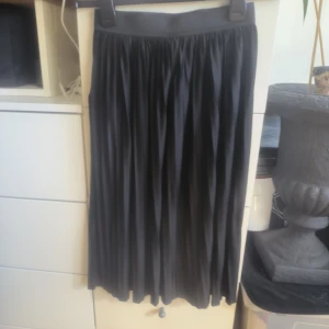 Svart kjol från JDY - Snygg svart kjol från JDY i en klassisk design. Kjolen har en elastisk midja och ett plisserat tyg som ger en fin rörelse. Perfekt för att skapa en stilren look.