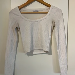 Vit ribbad croppad topp från Bershka - Säljer en vit ribbad croppad topp från Bershka. Toppen har långa ärmar och en rund halsringning, perfekt för en stilren look. Passar bra till både jeans och kjol. Perfekt för vår och sommar!